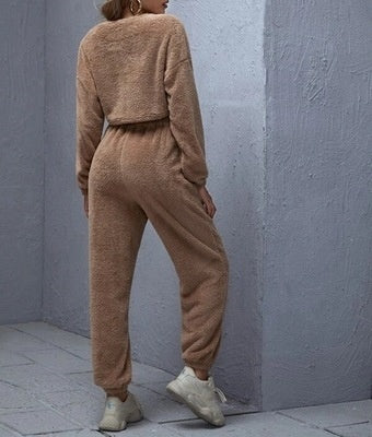 Person wearing a brown fleece tracksuit against a gray wall.