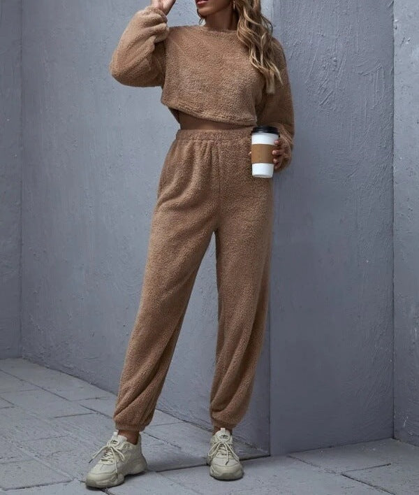 Person wearing a brown outfit holding a coffee cup against a gray wall.