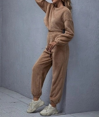 Person wearing a beige tracksuit against a gray wall