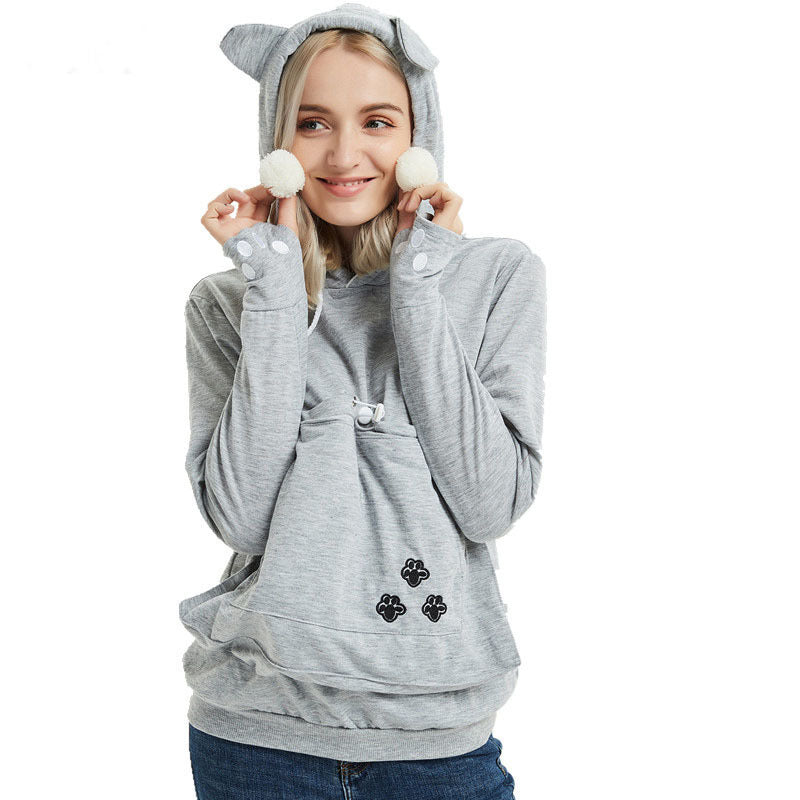 Person wearing a gray hoodie with cat ears and paw prints on a white background
