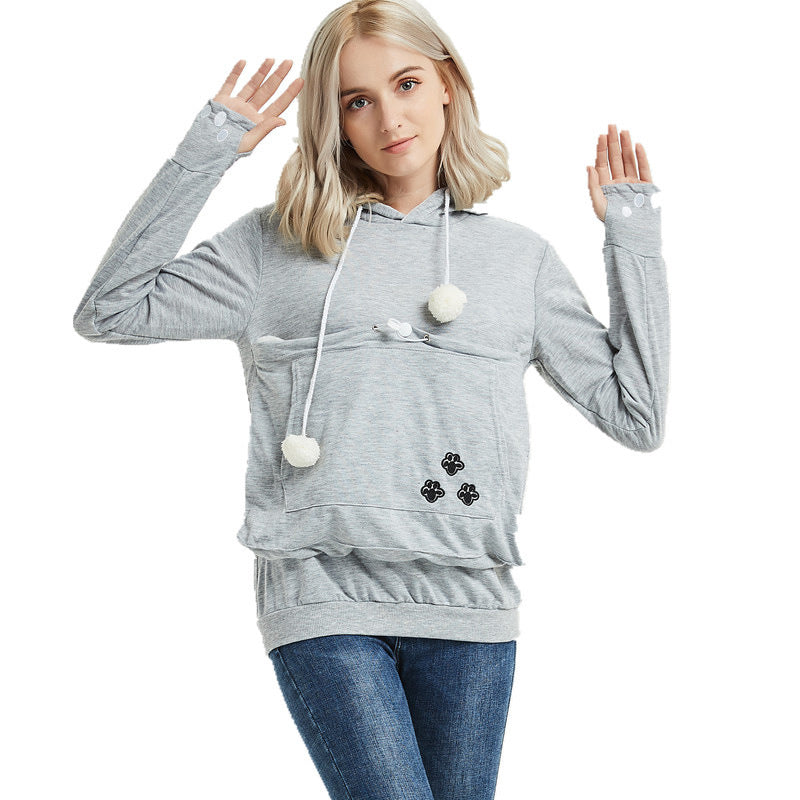 Woman wearing a gray hoodie with pom-pom details on a white background