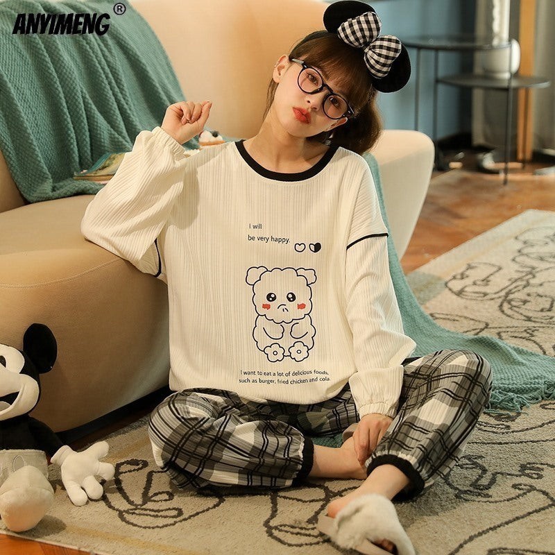 Child wearing a white long-sleeve shirt with a bear design and plaid pants, sitting on a couch.