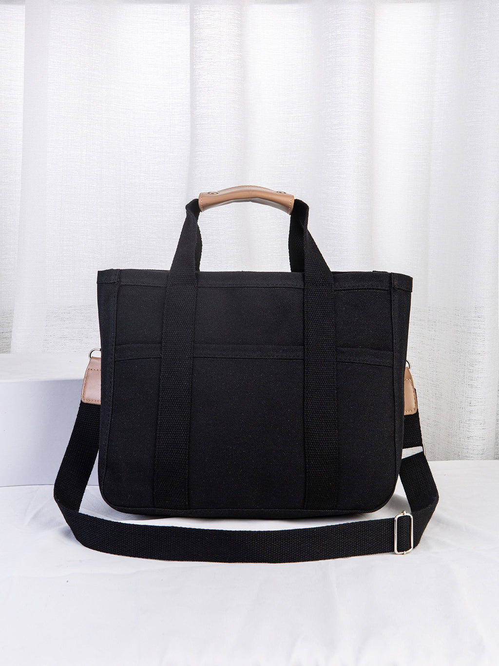 Black tote bag with a wooden handle on a white background
