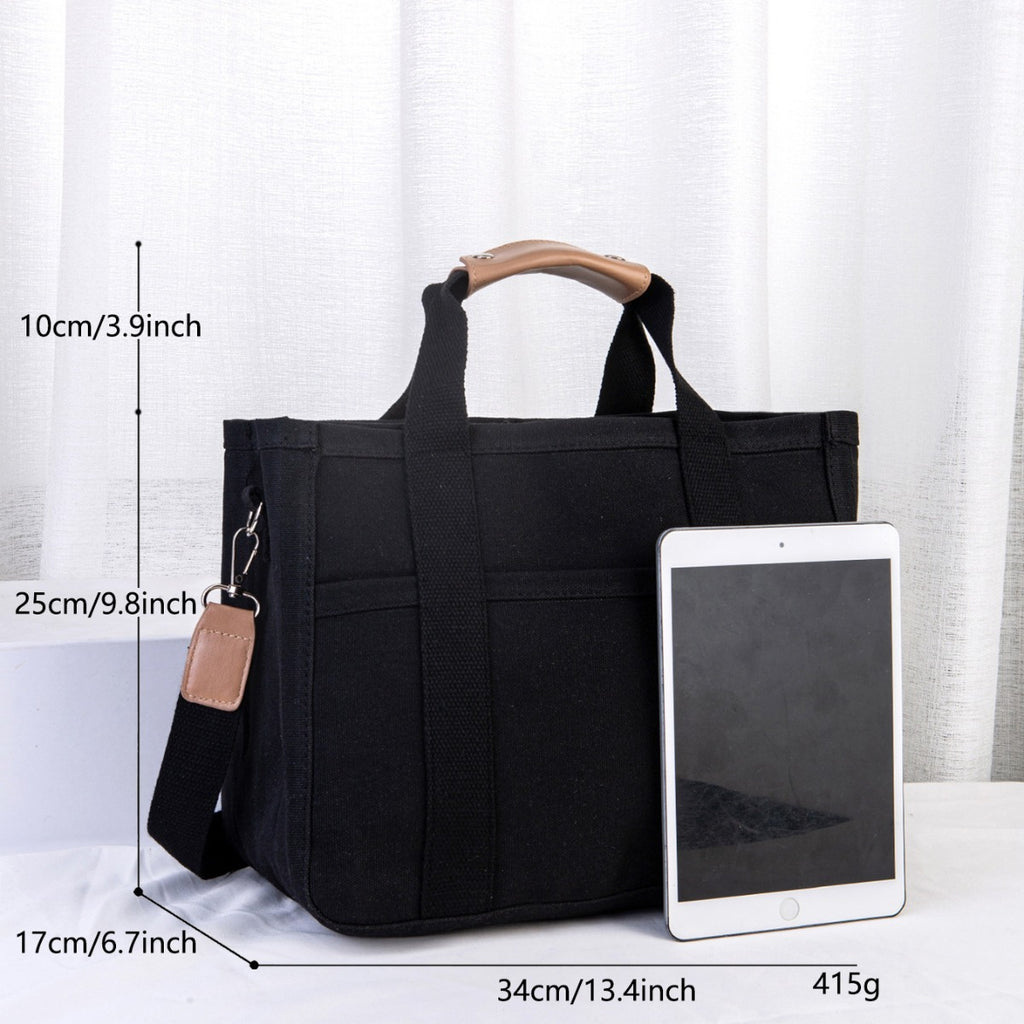 Black tote bag with measurements and an iPad for scale on a white background