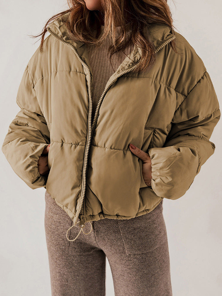 Person wearing a beige puffer jacket on a plain background