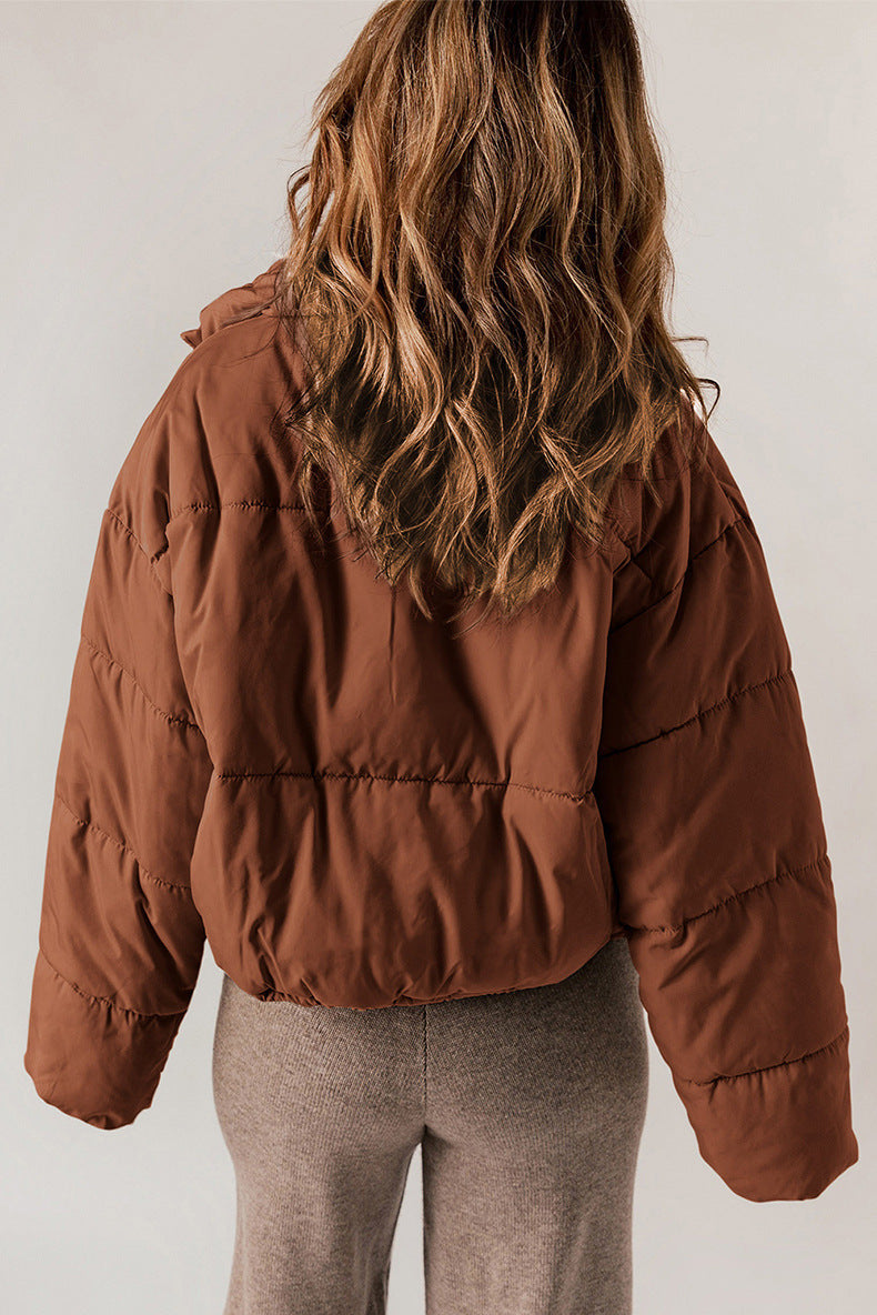 Person wearing a brown puffer jacket from behind on a plain background