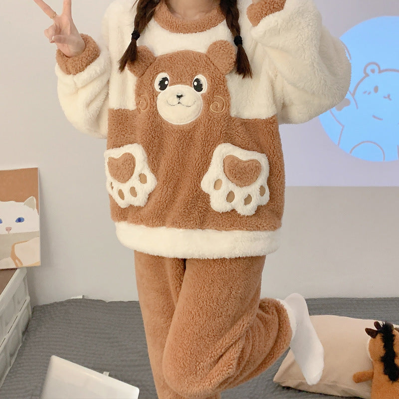 Person wearing a brown bear-themed onesie in a room with a cat plush toy.