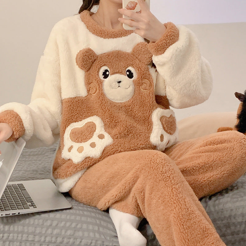Person wearing a brown teddy bear-themed pajama set sitting on a couch with a laptop.