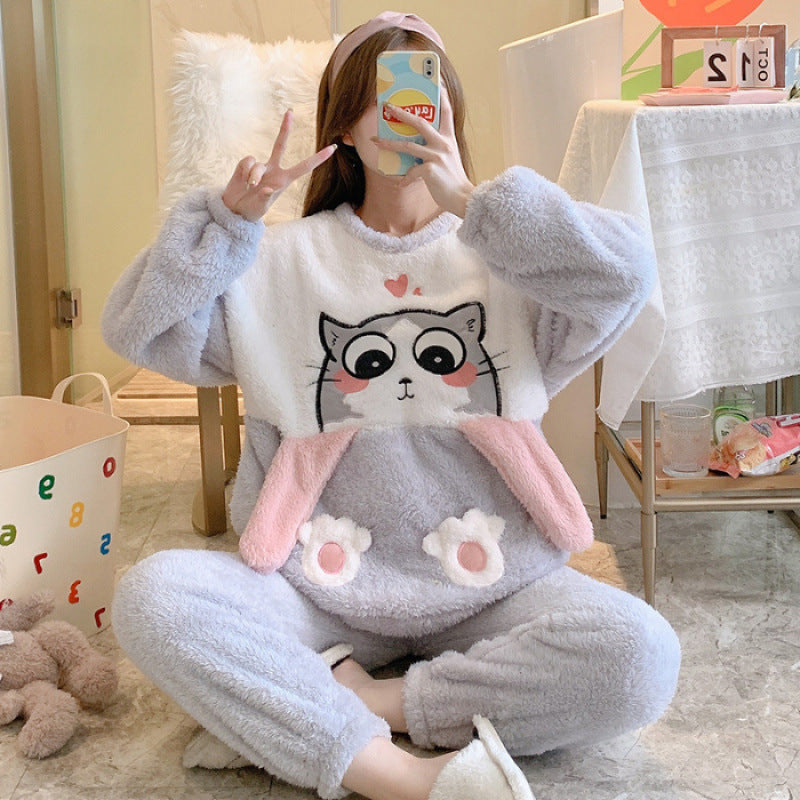 Person wearing a gray plush pajama set with a cat design, sitting on the floor.
