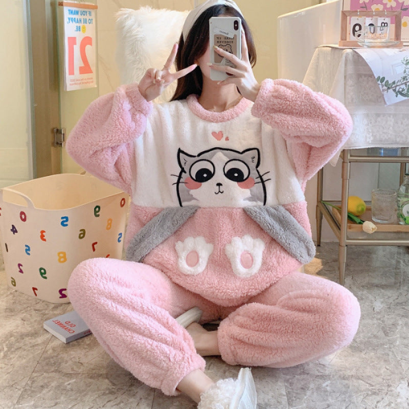 Person wearing a pink plush pajama set with a cartoon design, sitting on the floor.
