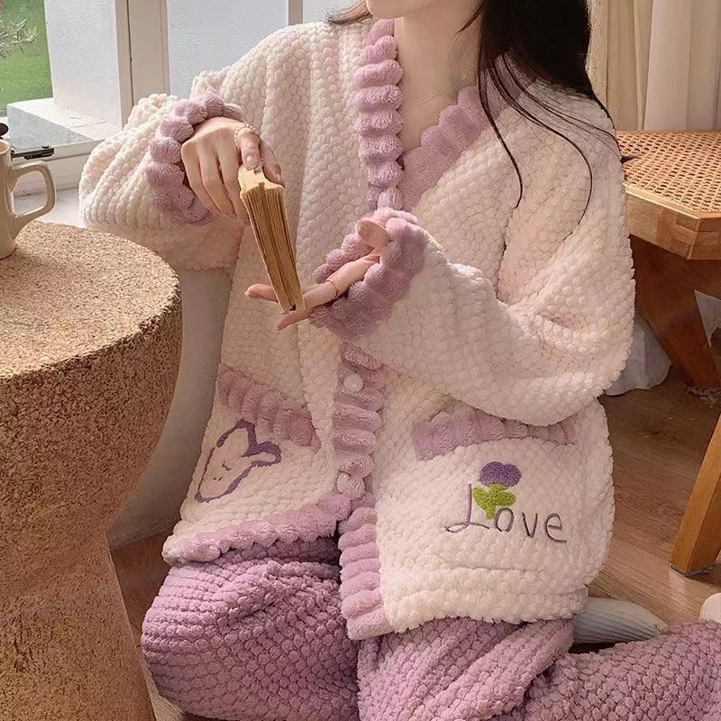 Person wearing a pink and white robe with 'Love' embroidery, sitting on a wooden stool.
