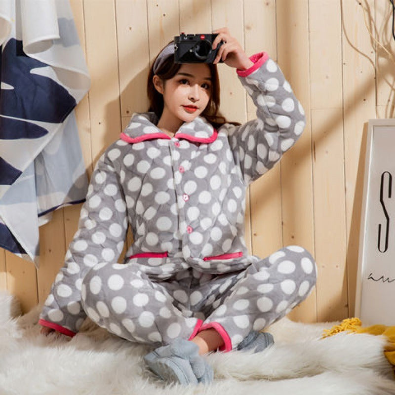 Person wearing gray polka dot pajamas with pink trim, sitting on a wooden floor.
