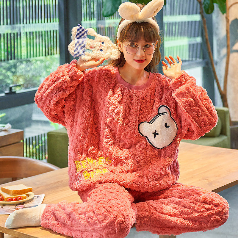 Person wearing pink plush pajamas with a cartoon design, sitting at a table.
