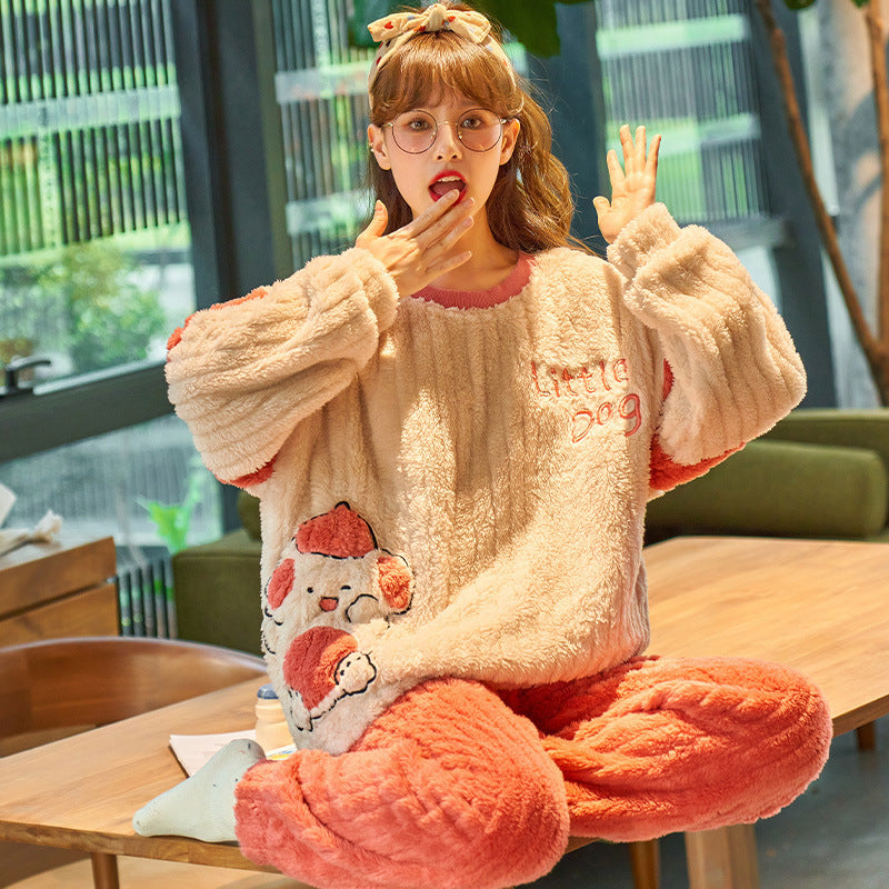 Person wearing a fluffy cream and pink pajama set with cartoon design, sitting on a table indoors.
