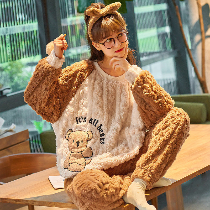 Person wearing a teddy bear-themed outfit with a sweater and pants, sitting at a table.